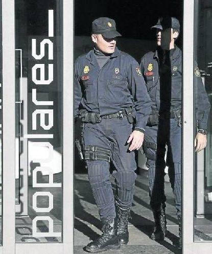 Dos agentes abandonan la sede del PP en la calle Génova de Madrid durante el registro ordenado por el juez Ruz. / Efe