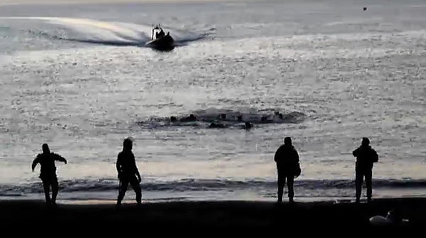 Agentes de la Guardia Civil esperan en la orilla la llegada de varios inmigrantes a las playas ceutíes el pasado día 6. / Efe