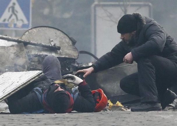 Un hombre trata de ayudar a un manifestante que resultó herido durante los disturbios entre opositores y policía, en Kiev (Ucrania), este mismo jueves. / Sergey Dolzhenko (Efe)