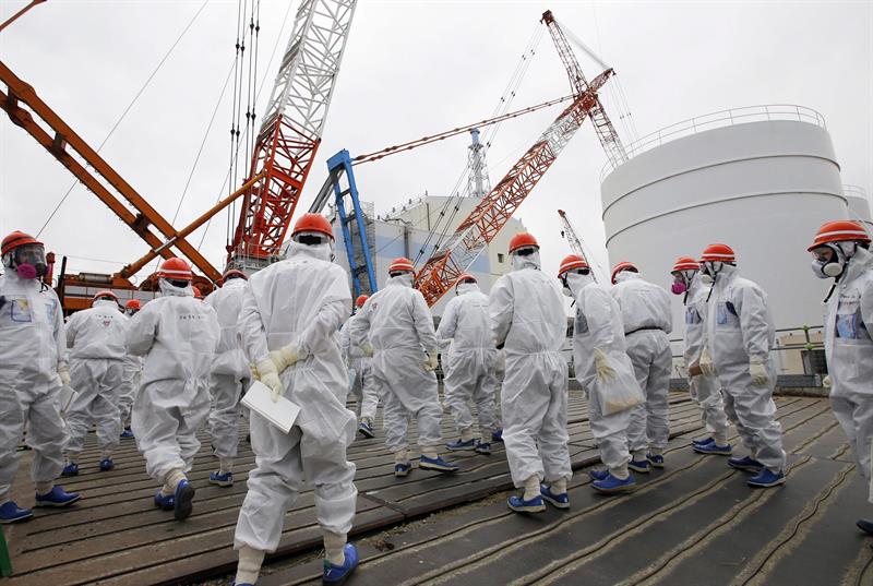 Miembros de Tokyo Electric Power (TEPCO) y periodistas con trajes y máscaras de protección durante su visita al control central de los reactores 1 y 2 de la planta de Daiichi en Fukushima (Japón) ayer lunes. / Toru Hanai (Efe)