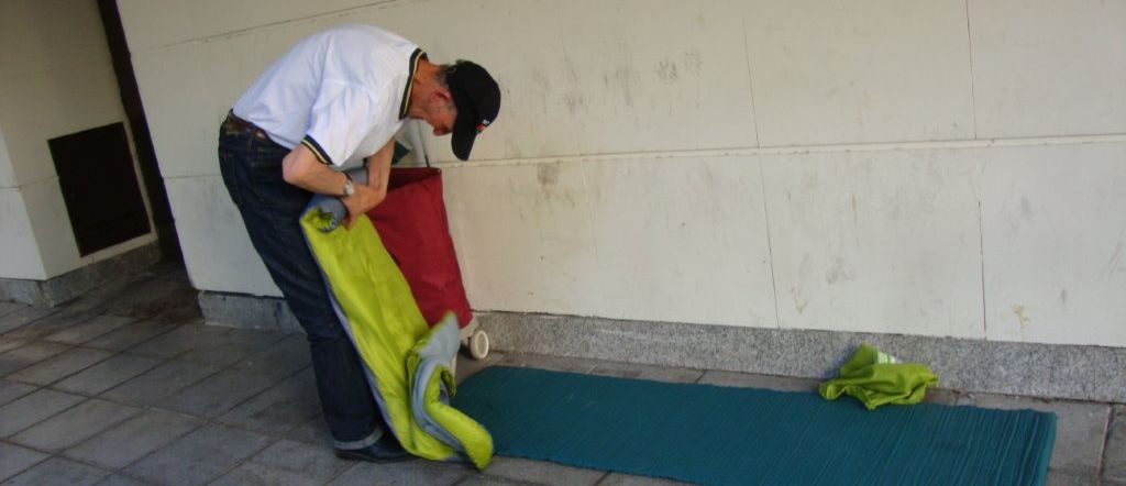 Livio Cozma recoge su saco de dormir tras una noche en los bajos de un conocido centro comercial, en Madrid. / B. Forcano