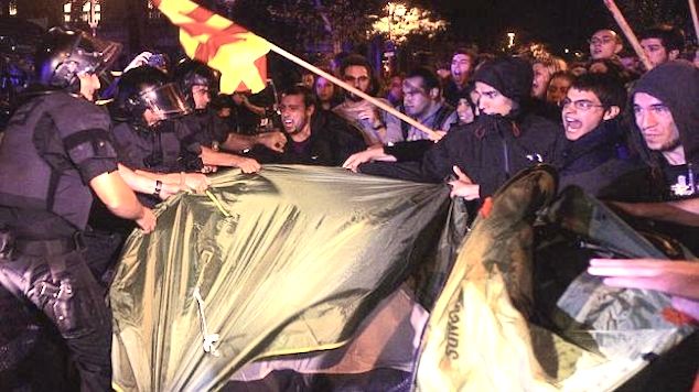 Forcejeo entre los agentes y los activistas que pretendían acampar, anoche, frente a la Delegación del Gobierno en Barcelona. / Captura de vídeo de YouTube