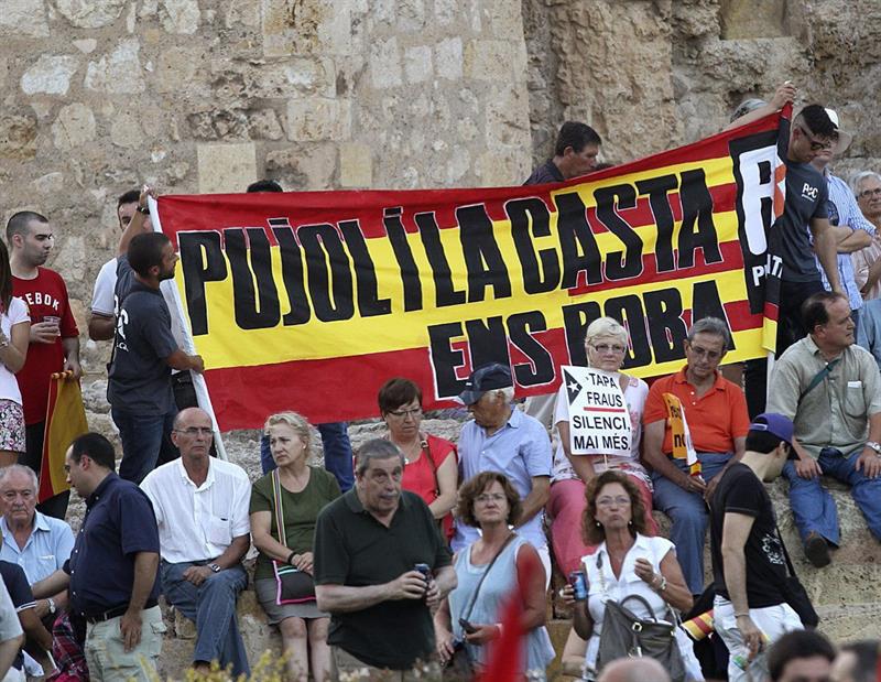 Manifestantes enarbolan una bandera con la leyenda "Pujol y la casta nos roban", durante la concentración convocada en Tarragona por la plataforma Sociedad Civil Catalana contra la independencia y bajo el lema "Recuperemos la sensatez, recuperemos la senyera". / Toni Garriga (Efe)