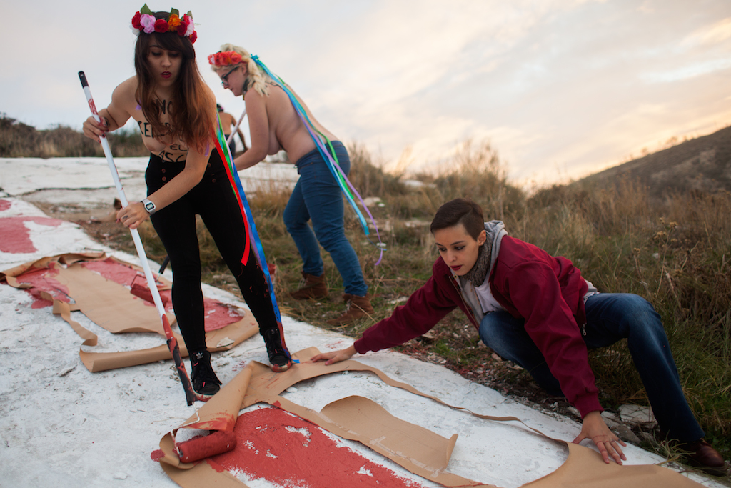 Las activistas de Femen pintando sobre la cruz del monte situado junto al cementerio de Paracuellos del Jarama, el lema "Stop 20N". / Alejandro Martínez Velez