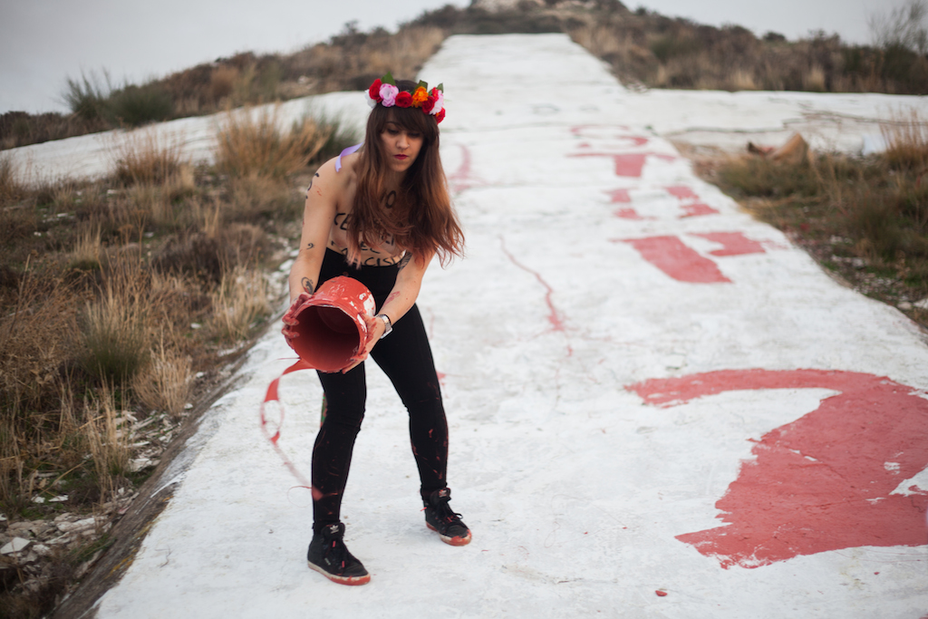 Lara, líder del movimiento Femen en España, arrojando el sobrante de pintura tras realizar la pintada. / A. M. V.