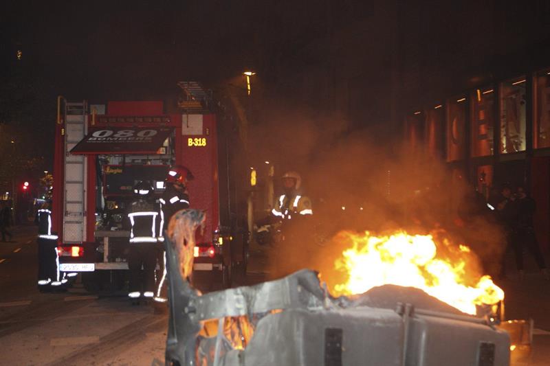 Un coche de bomberos junto a junto a un contenedor ardiendo en la calle Córcega, en las inmediaciones de la sede de Convergència Democrática (CDC). / Toni Garriga (Efe)