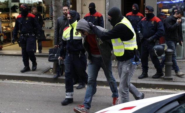 Mossos d'Esquadra escoltan a un detenido en la calle Gran de Sant Andreu durante la operación antiterrorista para desarticular una organización anarquista a la que se atribuyen diversos atentados con artefactos explosivos. / Alejandro García (Efe).