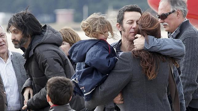 Los periodistas Garcia, a la izquierda, y Espinosa, abrazado a su mujer, a la llegada al aeropuerto de Barajas tras ser liberados. / Efe