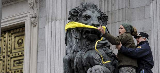Imagen de archivo de un activista de Greenpeace intentando amodazar a uno de los leones del Congreso en una protesta con la la Ley de Seguridad Ciudadana. / Pedro Armestre (Efe)