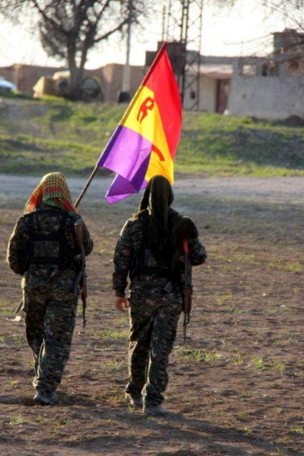 Los brigadistas se alejan tras la entrevista llevando la bandera de la República. / Comité Rojava