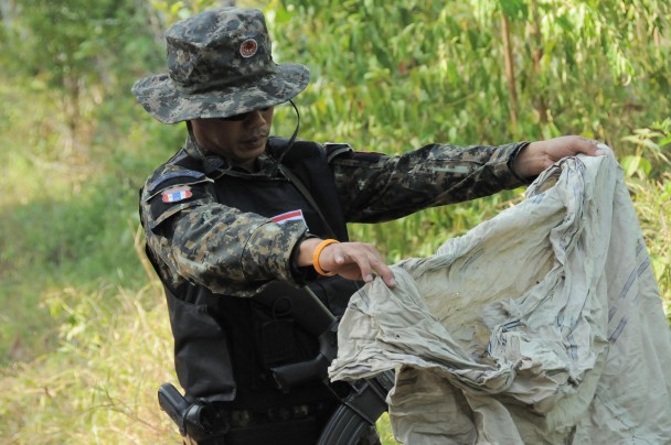 Un voluntario dedicado a la búsqueda de mafias y víctimas examina restos de sacos abandonados en la jungla tailandesa. (Mónica G. Prieto)