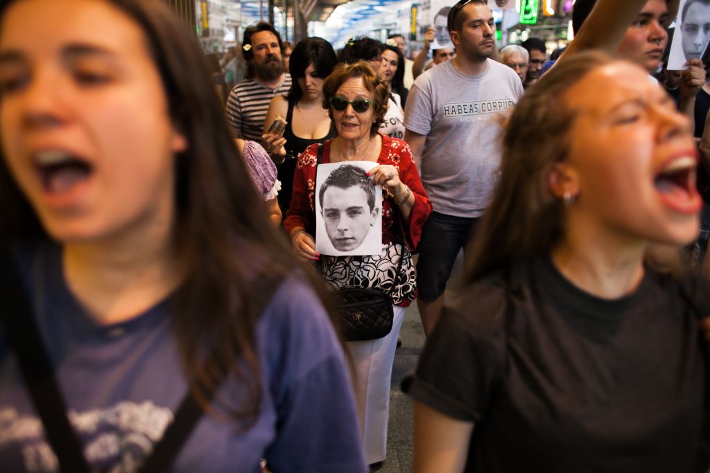 Una mujer, en el centro de la imagen, portando una imagen de la cara de Alfon durante la manifestación.