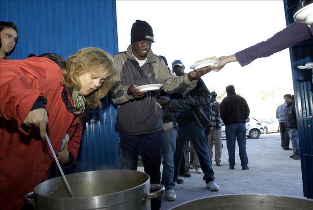 Imagen de archivo de un grupo de Inmigrantes esperando su turno para recibir comida de Cáritas. / Efe