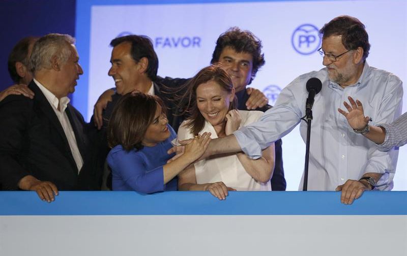 Mariano Rajoy, junto a su mujer y sus más directos colaboradores, estrecha la mano de Soraya Sáenz de Santamaría en el balcón de la sede del PP en la calle Génova. / Javier Lizón (Efe)