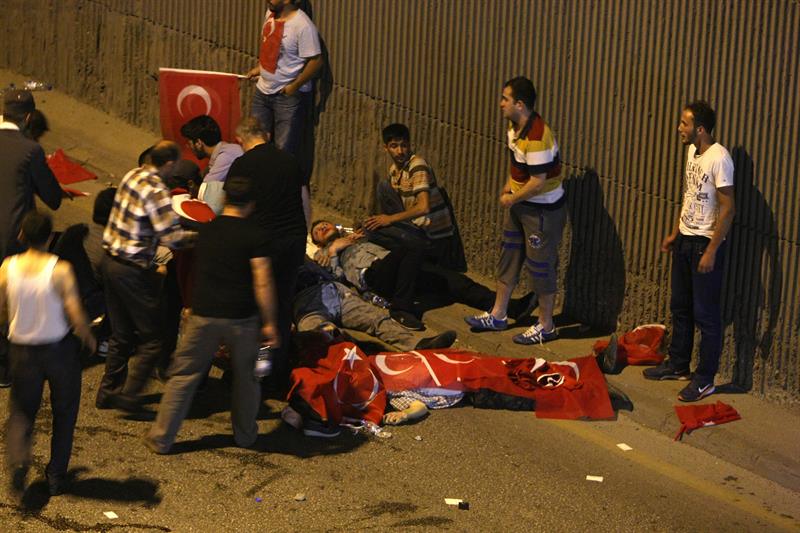 Un grupo de personas atiende a los heridos en Ankara y tapa con banderas turcas a varios fallecidos. / STR (Efe/Epa)