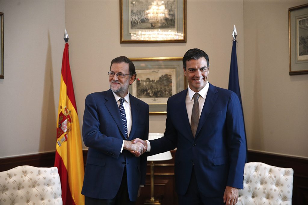 El presidente del PP y del Gobierno, Mariano Rajoy, y el secretario general del PSOE, Pedro Sánchez, se saludan en una reunión del año pasado en agosto.