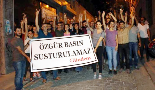 Los periodistas liberados frente a la sede clausurada del periódico. La pancarta dice "La prensa liber no se puede cerrar". / Ozgur Gundem