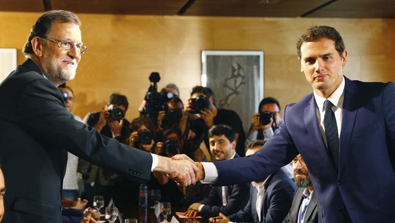 Mariano Rajoy y Albert Rivera, esta mañana, en el Congreso, apretándose la mano tras el acuerdo para la investidura firmado por sus portavoces parlamentarios. / J. P. Gandul (Efe)
