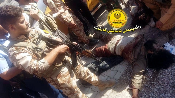 Miembros de la Policía kurda junto al cuerpo de dos yihadistas que acaban de ser abatidos en Kirkuk (Irak). / Bas News