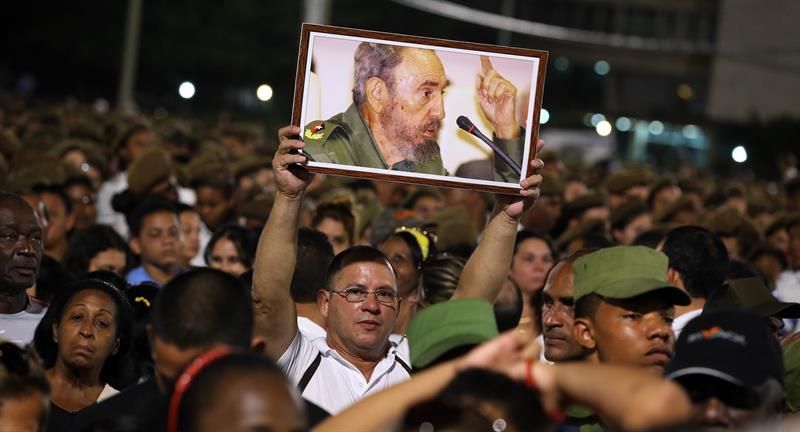 Un ciudadano muestra un cartel con la imagen de Fidel durante el homenaje.