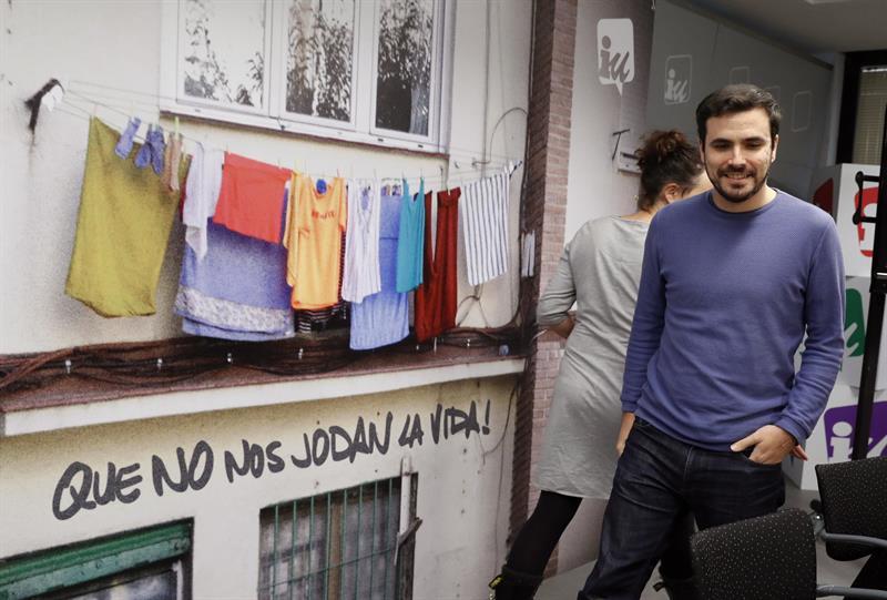 Alberto Garzón, ante el cartel de la campaña 'Que no nos jodan la vida'.