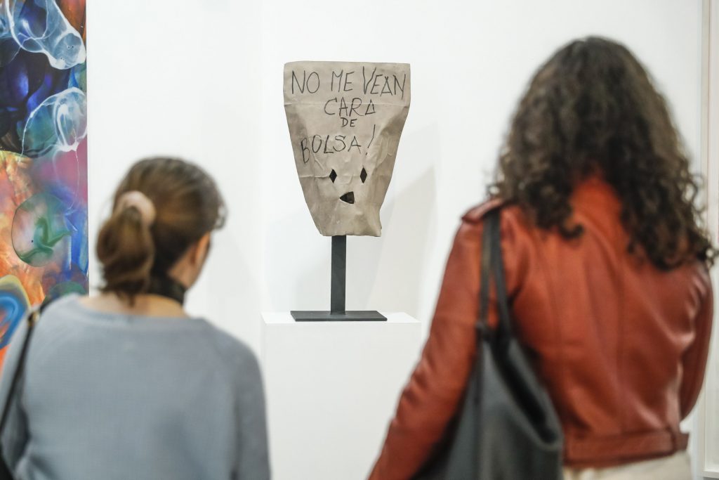 Dos mujeres contemplan "Venezuela" P.U., de la serie Máscaras contemporáneas 2017, del artista español Fernando Sanchez Castillo