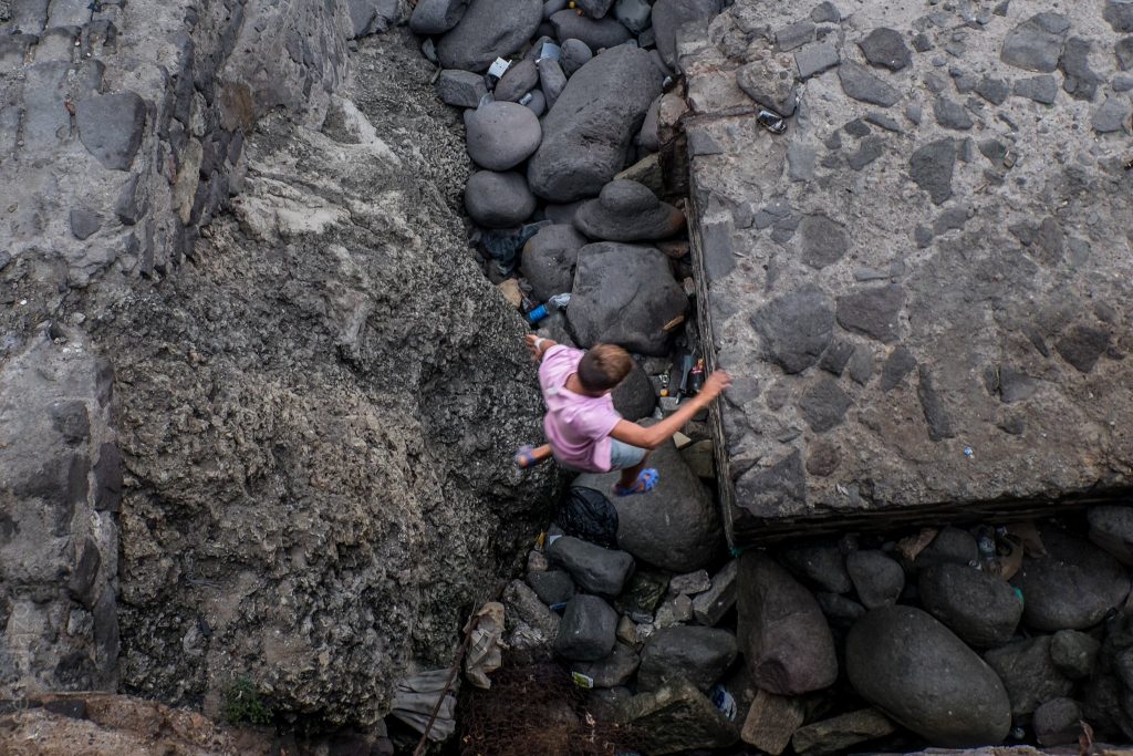 Un niño arriesga la vida al saltar entre las rocas del puerto en Melilla