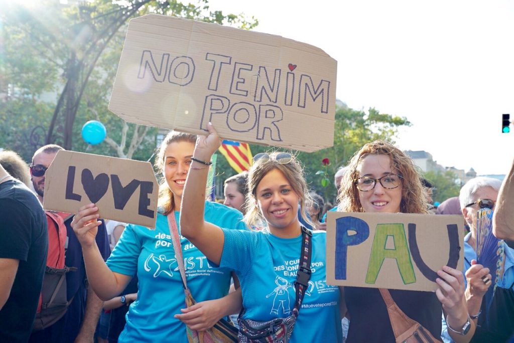 Tres chicas enseñan a la cámara sus carteles confeccionados con trozos de cartón.