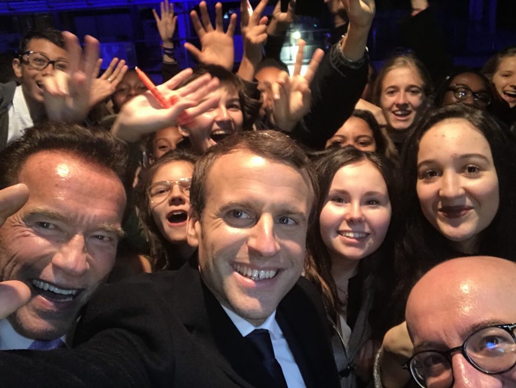 Arnold Schwarzenegger, Emmanuel Macron y el primer ministro belga Charles Michel posan junto a un grupo de adolescentes