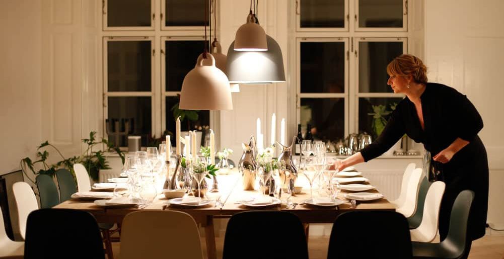 Una mujer prepara una mesa para una cena.