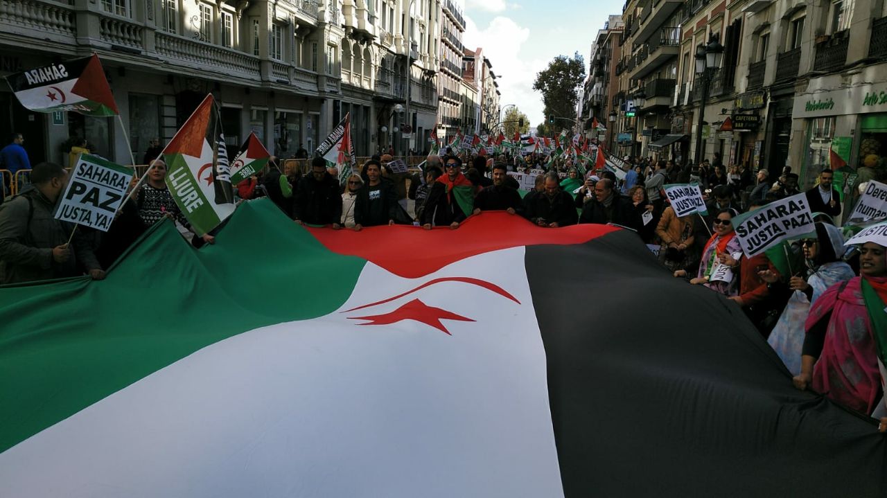 Varios manifestantes sujetan una gran bandera del Sahara Occidental durante la marcha.