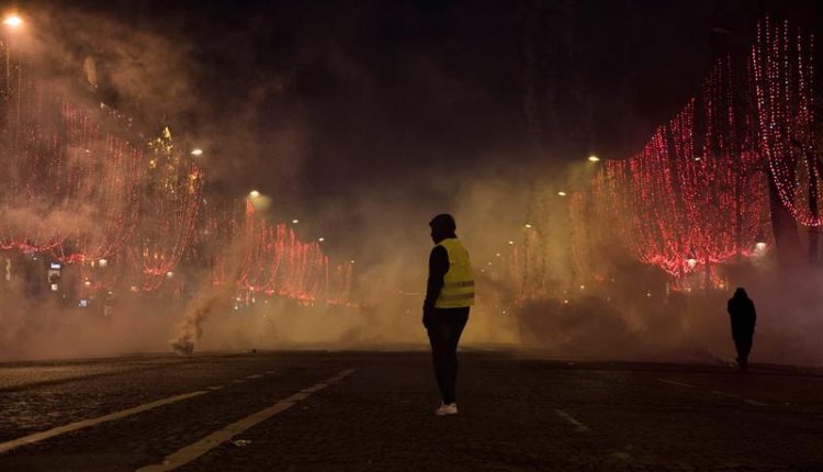 Un manifestante de chaleco amarillo está parado en medio del humo durante una manifestación en París, Francia, el 8 de diciembre. / EFE